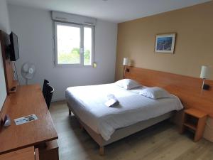 1 dormitorio con cama, mesa y ventana en Séjours & Affaires Grenoble Marie Curie en Grenoble