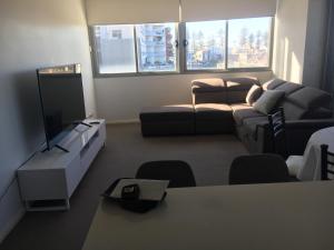 a living room with a couch and a tv at Ocean view 2 Bedroom apartment in Sydney