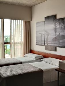1 dormitorio con 2 camas y una ventana con tabla de surf en 9006 Suites Natal Vista Mar, en Natal
