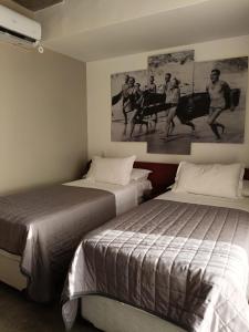 a bedroom with two beds and a painting on the wall at 9006 Suites Natal Hotel in Natal