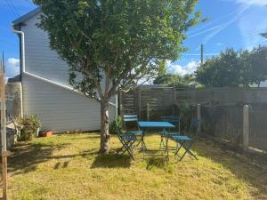 una mesa y sillas bajo un árbol en un patio en Appartement 35 m2 1er étage 200 m de la mer avec jardin, en Luc-sur-Mer