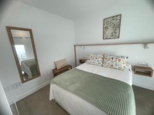 a white bedroom with a bed and a mirror at Ventana del Nublo 1D in Tejeda