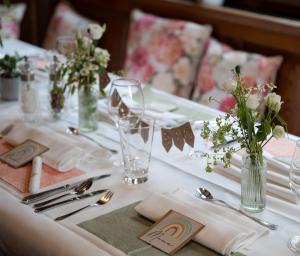 a table with a white table set with silverware and flowers at Hotel Restaurant Rebstock in Oppenau
