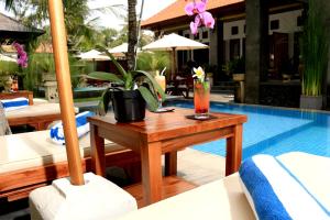 einen Tisch mit einem Getränk darauf neben einem Pool in der Unterkunft Kubu Garden Suites & Villas Nusa Dua in Nusa Dua