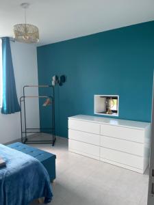 a bedroom with a blue wall and a white dresser at Chez Marjo & Flo in Gageac-et-Rouillac