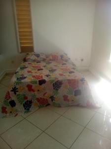 a bed with a flowered bedspread on the floor in a room at My Zayanda in Les Abymes