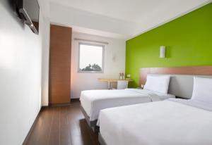 a hotel room with two beds and a green wall at Amaris Hotel Citra Raya &ndash; Tangerang in Tangerang