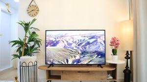 a television on a stand in a living room with a clock at Dainty 1BR Apartment in Masdar - Cozy Stay Near Masdar Park & City Centre in Abu Dhabi