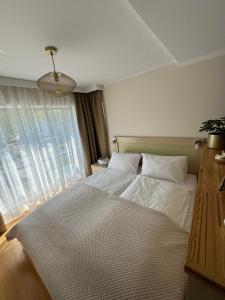 ein Schlafzimmer mit einem großen weißen Bett mit einem Fenster in der Unterkunft Nord House Apartament in Jastrzębia Góra