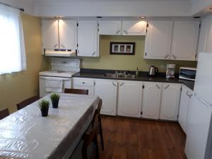 a kitchen with white cabinets and a table in it at Lands End Vacation Home in Twillingate