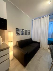 ein Wohnzimmer mit einer schwarzen Couch vor einem Fenster in der Unterkunft Residenza Elegante - A 5 fermate dal Duomo in Mailand