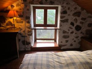 a bedroom with a window in a stone wall at Chalé na Montanha Casa de Baixo in Manteigas