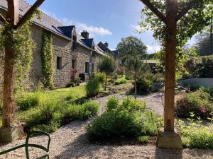 un giardino con una casa in pietra con fiori e piante di Encore une fois, La maison coloréé a Locmalo