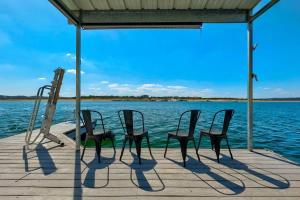 four chairs sitting on a dock next to the water at Atlantis - Front Row View of Lake Travis in Leander
