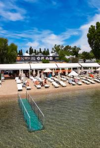 a beach with chaise lounges and chairs on the water at Manuela Boutique Hotel Bitez in Bitez