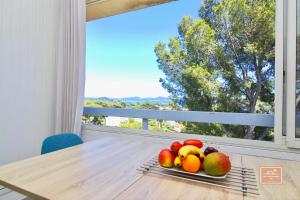 a plate of fruit on a table in front of a window at La Digue, 2 chambres, vue mer et piscine in La Seyne-sur-Mer