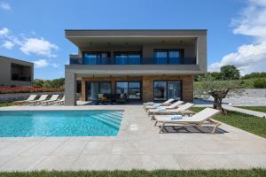 a house with a swimming pool and lounge chairs at Villa Skalica Pomer - Medulin SEA VIEW in Pomer