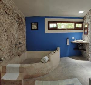 a bathroom with a tub and a blue wall at Hacienda San Francisco Tzacalha in Dzidzantún