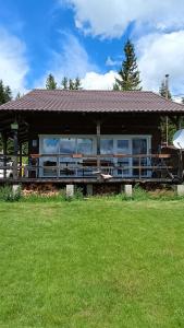 a large house with a porch on a grass field at Casuta Schiorului in Mărişel