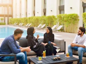 un grupo de personas sentadas frente a una piscina en Mövenpick Hotel Tahlia Jeddah, en Yeda