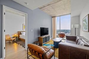 una sala de estar con un sofá y un televisor en Modern 1BR Condo on Rainey St with Pool and Views, en Austin