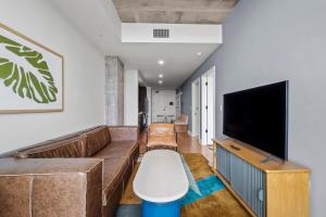 a living room with a couch and a flat screen tv at Modern 1BR Condo on Rainey St with Pool and Views in Austin