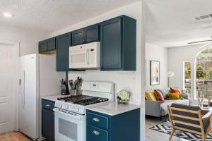 una cocina con armarios azules y un horno de fogón blanco en Charming East Side Bungalow, en Austin 9 fotos más