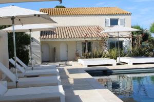 海濱聖瑪麗的住宿－Mas des Cabidoules，一座带游泳池和两把遮阳伞的房子
