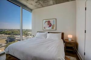 ein Schlafzimmer mit einem weißen Bett und einem großen Fenster in der Unterkunft High Rise in the heart of ATX in Austin