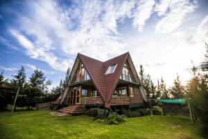une maison avec un toit mansardé sur une pelouse verte dans l'établissement The Besotted Cottage at Mount Kenya Farm Stay, à Naro Moru