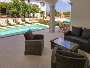 a patio with a pool and chairs and a couch and a table at La Casa di Emy in Budoni