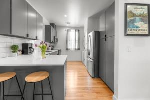 a kitchen with a refrigerator and two bar stools at Modern Condo with Parking - B in Austin