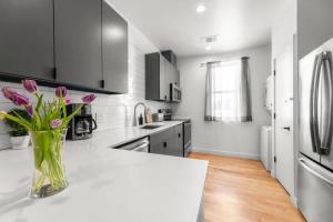 a white kitchen with a vase of flowers on a counter at Modern Condo with Parking - B in Austin +18 photos