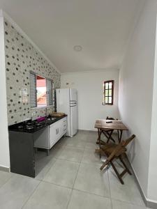 uma cozinha com um fogão, um frigorífico e uma mesa em Flats Bem Te Vi - Praia Grande em Ubatuba