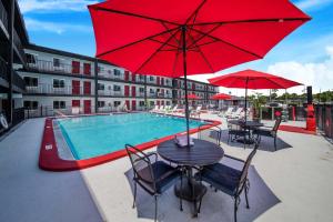 una piscina con mesas y sillas y una sombrilla roja en Seasons Florida Resort en Kissimmee