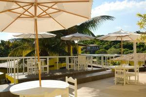 a patio with tables and chairs and umbrellas at Pousada Gente Bonita La Mansion in Búzios