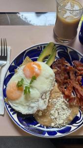 a plate of food with eggs and bacon and a drink at Hacienda Las Amantes in San Miguel de Allende