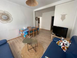 salon z niebieską kanapą i stołem w obiekcie Les Platanes - Renoir Rez de chaussée w mieście Lamalou-les-Bains