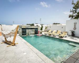 a swimming pool with chairs and a fireplace at Jasmin Villas Djerba in Mezraya