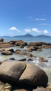 um grupo de rochas na água em uma praia em Flats Bem Te Vi - Praia Grande em Ubatuba