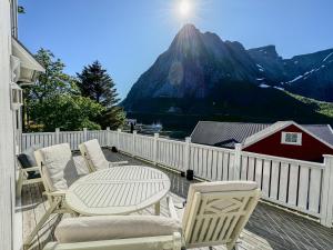 a patio with a table and chairs and a mountain at Husly Reine - your home with Reinebringen view in Reine