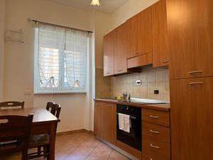 罗马Oderisi crossroads的厨房配有木制橱柜、桌子和窗户。 更多9张照片