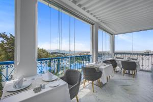 un restaurante con mesas y sillas blancas y ventanas grandes en La Menara Hotel & SPA, en Sidi Bou Saïd
