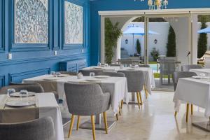 um restaurante com mesas e cadeiras brancas e paredes azuis em La Menara Hotel & SPA em Sidi Bou Said