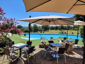 a patio with tables and umbrellas in front of a pool at Chalets de l'Oasienne in Lissac et Mouret