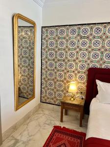 a bedroom with a mirror and a table with a bed at La Menara Hotel & SPA in Sidi Bou Saïd