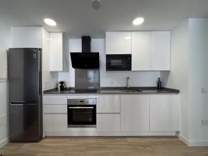 a kitchen with white cabinets and a black refrigerator at Infinito in La Oliva