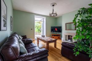 a living room with a leather couch and a table at Holmfield House in Clayton West