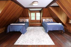 two beds in a room with wooden walls and wooden floors at Quietude - A 60-Acre Historic Mountain Estate with 10 bedrooms in Tuftonboro