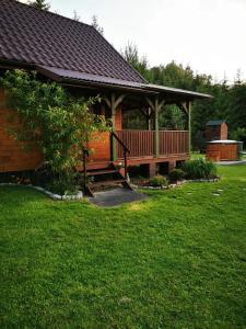 a large wooden cabin with a deck on the grass at Letniczówka Guciów-Pokochaj Roztocze in Guciów